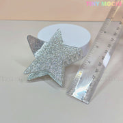 The Tiny Mochi Star Hair Claw Clip—Large Glitter Star Clip for Thick Hair—shaped like a silver star, sparkles beside a transparent ruler and white round object. This Y2K acetate hair accessory measures about 8 cm long.