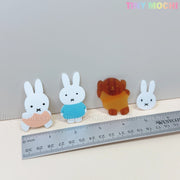 Four Kawaii Bunny & Bear Acrylic Hair Clips by Tiny Mochi—an orange bunny, blue bunny, brown bear, and small bunny face—are lined up by a ruler. The “Tiny Mochi” logo appears at the top right.