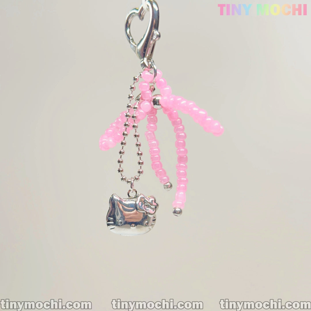 A cute keychain by Tiny Mochi featuring pink beads, a bow, and a kitty charm—ideal for coquette aesthetics. The pale background shows TINYMochi in colorful letters at the top right corner.
