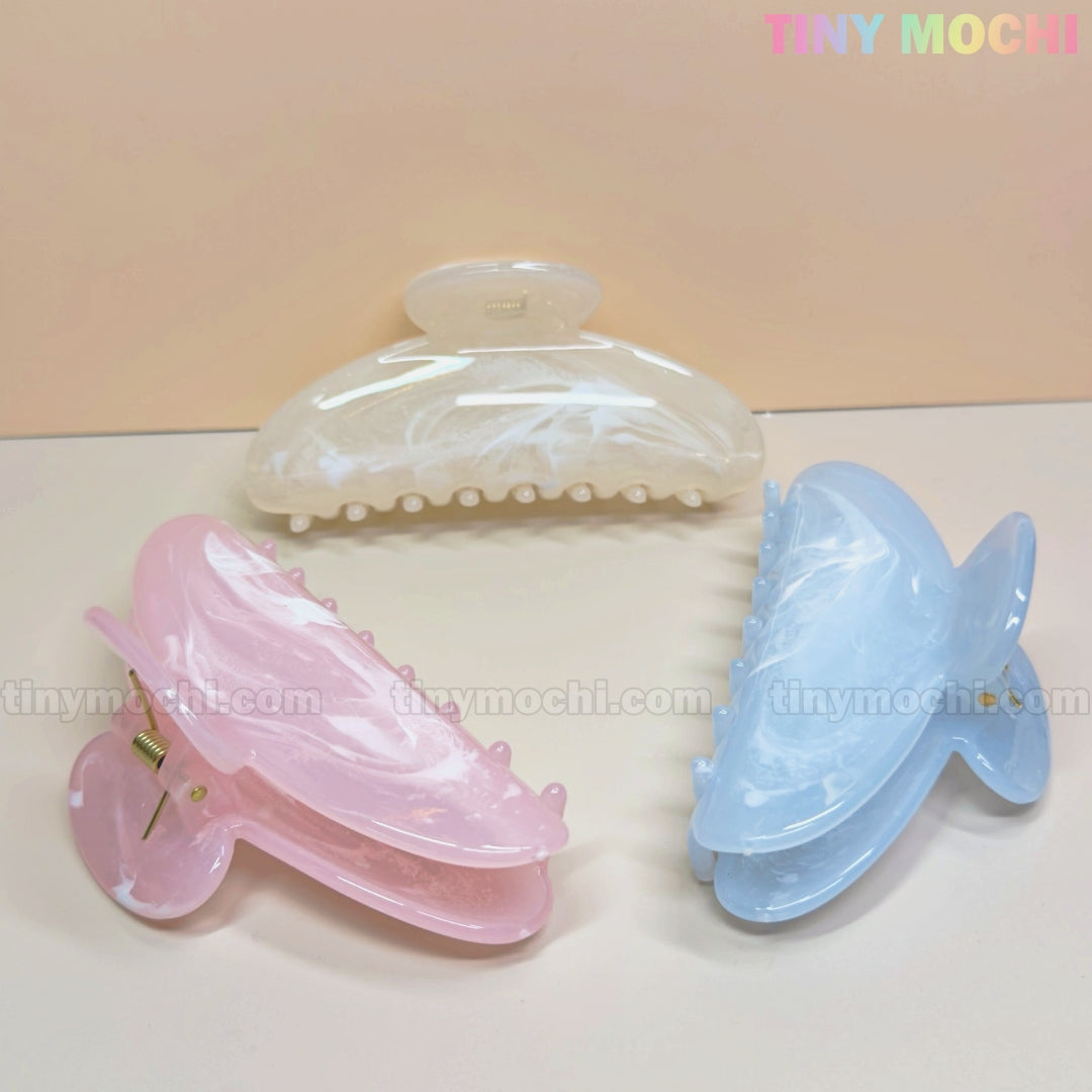 Three large pastel marble crescent-shaped hair claw clips (white, pink, blue) from Tiny Mochi are arranged in a triangle. Made of durable 11cm pastel acetate acrylic, each shark clip is perfect for thick hair. Tiny Mochi appears in pastel at the top right.