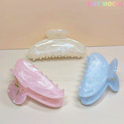 Three large pastel marble crescent-shaped hair claw clips (white, pink, blue) from Tiny Mochi are arranged in a triangle. Made of durable 11cm pastel acetate acrylic, each shark clip is perfect for thick hair. Tiny Mochi appears in pastel at the top right.