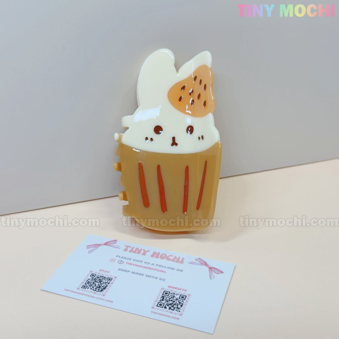 The Kawaii Cupcake Bunny Hair Claw Clip – Strawberry Dessert Style by Tiny Mochi, a cute acrylic hair accessory for women & girls, is shown beside a Tiny Mochi business card on a light background.