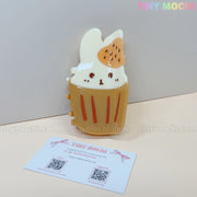 The Kawaii Cupcake Bunny Hair Claw Clip – Strawberry Dessert Style by Tiny Mochi, a cute acrylic hair accessory for women & girls, is shown beside a Tiny Mochi business card on a light background.