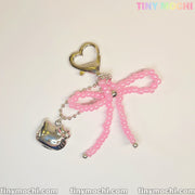 The Pink Beaded Bow & Kitty Charm—Cute Keychain Bag Charm for Coquette Aesthetic by Tiny Mochi features a gold heart-shaped clasp, pink beaded bow, and silver kitty charm. The image shows the Tiny Mochi logo in pastel at the top right corner.