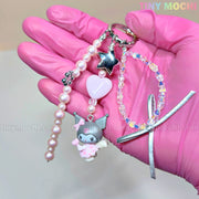 A hand in a pink glove holds the Tiny Mochi Kawaii Angel Charm Keychain Kit, a Sanrio-inspired DIY set with pearls, ribbon, star, pink heart, My Melody charm, and beaded bracelet—perfect for making cute phone or bag accessories.