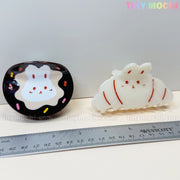 Two Tiny Mochi Kawaii Bunny Hair Claw Clips, in donut sprinkle and croissant designs, are shown beside a ruler. The cute acrylic accessories feature the Tiny Mochi brand on the clips and in the image corner.