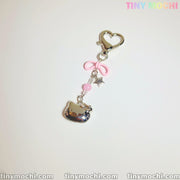 The Pink Kitty Bow Charm by Tiny Mochi is a cute phone or bag accessory featuring a silver heart clasp, pink bow and bead, silver star, and shiny kitty charm—perfect for coquette lovers. Displayed on white with Tiny Mochi branding.