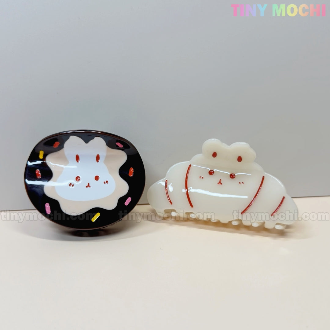 The Tiny Mochi Kawaii Bunny Hair Claw Clip features a cute acrylic bunny in either Donut Sprinkle or Croissant design—adorable, charming facial features make it the perfect stylish hair accessory.