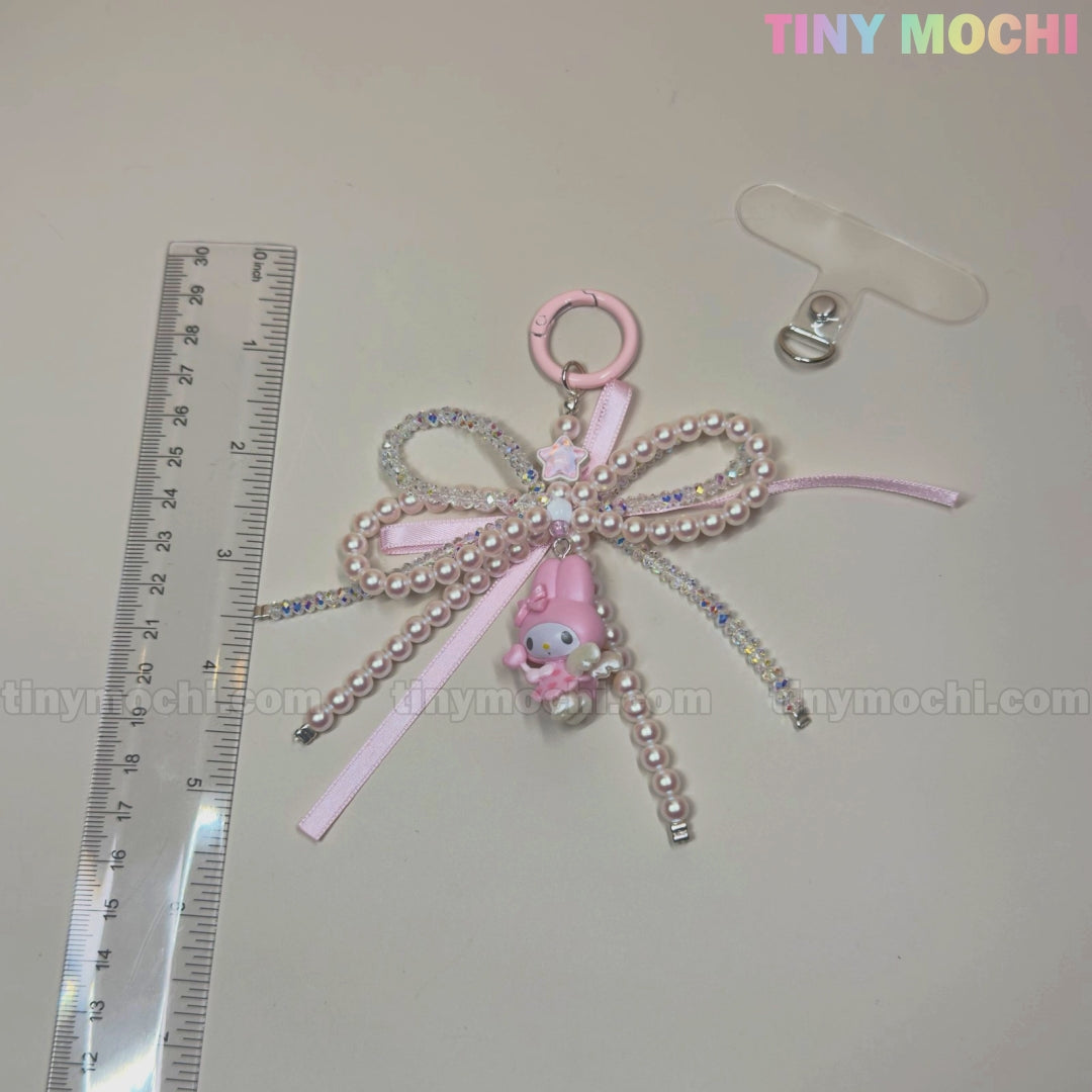 The Tiny Mochi Kawaii Bow Charm Keychain with pearl and ribbon makes a cute Coquette Angel bag charm or DIY phone accessory gift. Shown beside a clear ruler and badge clip, with TINY MOCHI in pastel on a light surface.