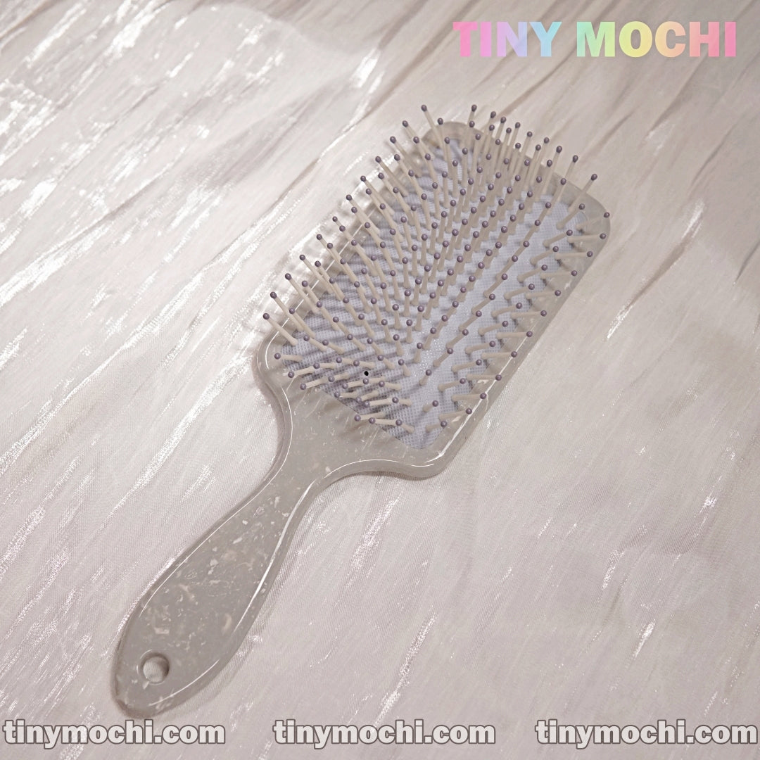 A Marble Pattern Detangling Brush - Nordic Style Paddle Hair Brush for Dry and Wet Hair by Tiny Mochi sits on a light, textured surface. TINY MOCHI appears in pastels at the top right; tinymochi.com repeats along the bottom edge.