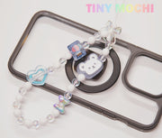 The Y2K Aesthetic Phone Charms Set by Tiny Mochi, featuring bear, butterfly, and heart charms on colorful lanyards, hangs over a black and clear case. “Tiny Mochi” appears in pastel at the top right, adding nostalgic vibes.