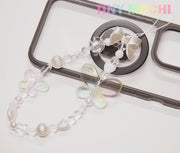 The Y2K Aesthetic Phone Charms Set from Tiny Mochi features bear, butterfly, and heart charms on colorful lanyards, adding playful vibes to your black phone case. The Tiny Mochi brand name appears in colorful letters in the top right corner.