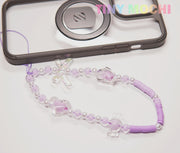 The Y2K Inspired Beaded Phone Strap by Tiny Mochi, featuring butterflies and hearts, is shown beside a black phone case on a white background. TINY MOCHI appears in colorful letters at the top right. Ideal for phones, AirPods, and more!.