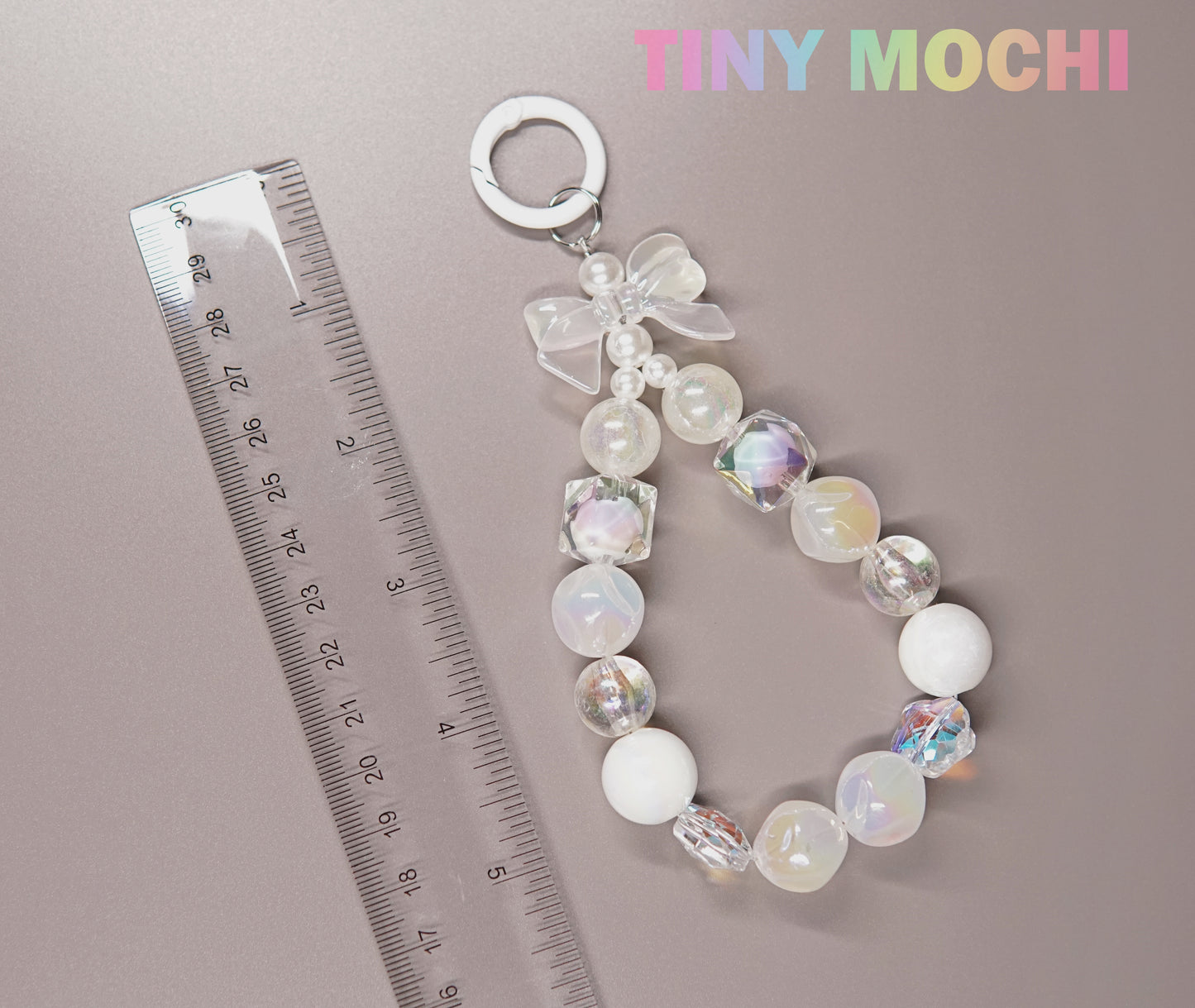 The Adorable Faux Pearl Bag Charm Keyring by Tiny Mochi is shown beside a transparent ruler, with TINY MOCHI in pastel on the top right—a cute accessory ideal as a backpack companion or beaded phone charm.