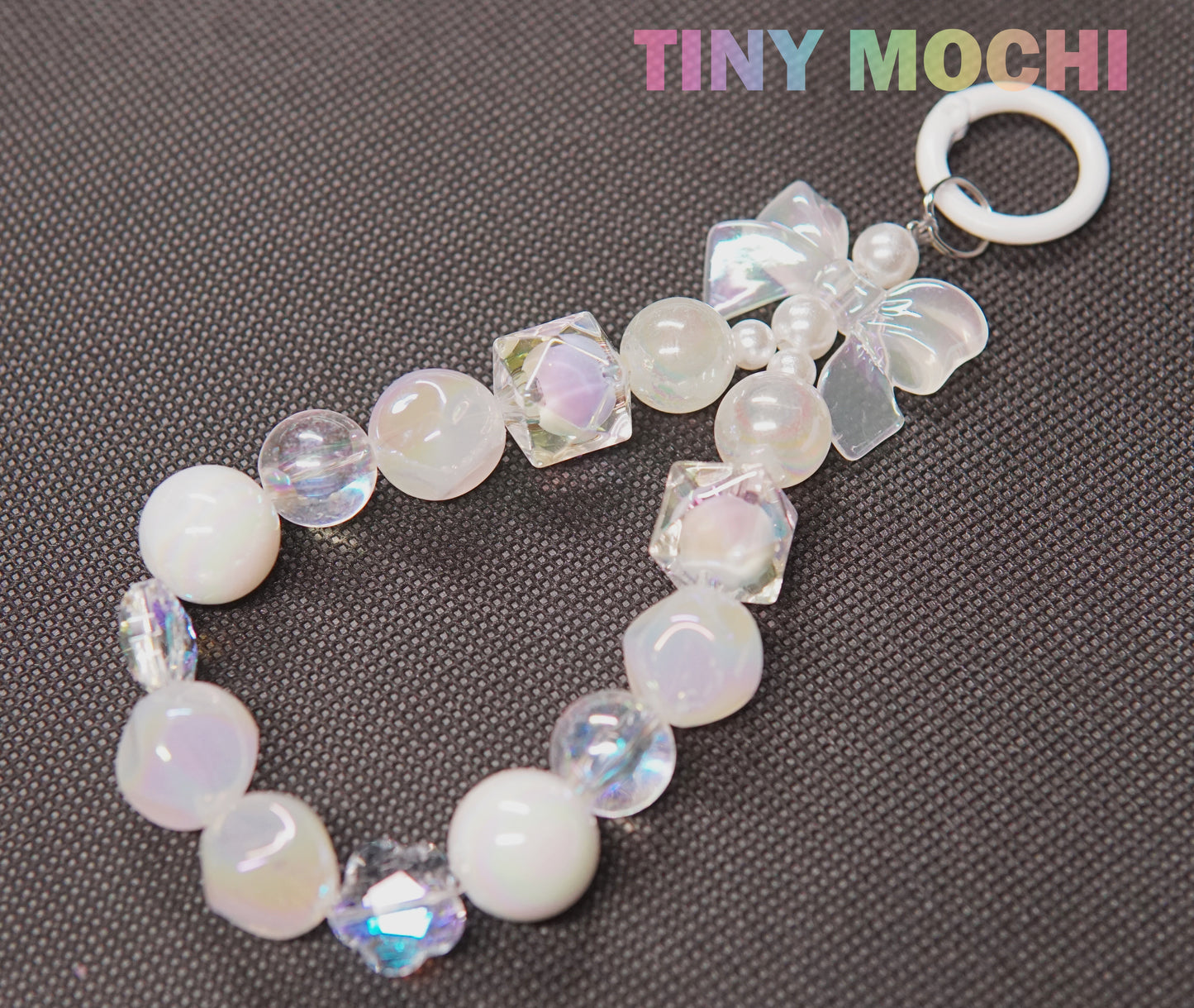 The Adorable Faux Pearl Bag Charm Keyring by Tiny Mochi features iridescent and pearl-like beads, clear cubes, and a butterfly charm—an ideal Bohemian accessory for your backpack or as a cute phone charm.