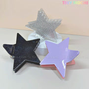 Three Star Hair Claw Clips in black, glittery silver, and lavender from Tiny Mochi sit on a round white platform with a beige background. These large Y2K acetate hair accessories are perfect for thick hair and are eco-friendly.