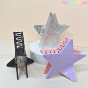 Three Tiny Mochi Star Hair Claw Clips—large glitter star clips for thick hair in silver, black, and lavender—are displayed on a neutral background with pastel TINY MOCHI text, evoking a playful Y2K acetate hair accessory vibe.