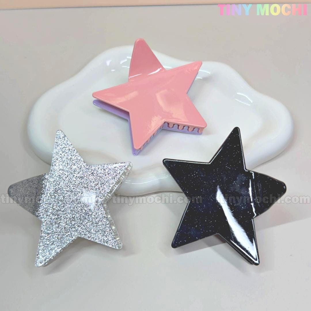 Three star-shaped hair clips, including the Large Glitter Star Hair Claw Clip for thick hair by Tiny Mochi, are shown on a white dish against a pastel background with TINY MOCHI text. A cute Y2K acetate hair accessory for any look!.