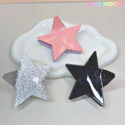 Three star-shaped hair clips, including the Large Glitter Star Hair Claw Clip for thick hair by Tiny Mochi, are shown on a white dish against a pastel background with TINY MOCHI text. A cute Y2K acetate hair accessory for any look!.