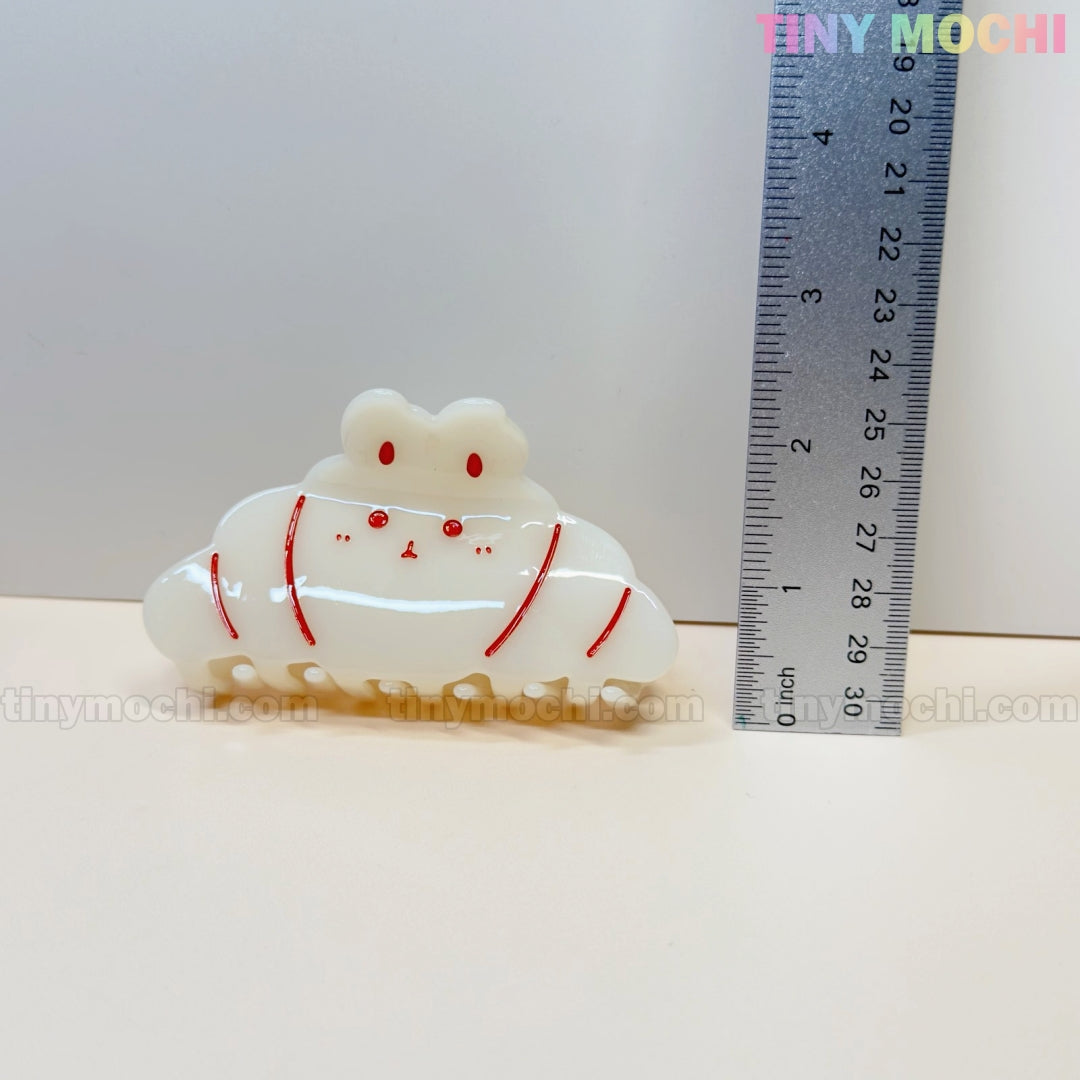 A cute acrylic hair clip from Tiny Mochi, shaped like a bunny in your choice of Donut Sprinkle or Croissant design, is shown next to a ruler for size. Approx. 5 cm wide—perfect for fans of kawaii hair accessories!.
