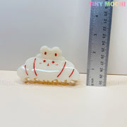 A cute acrylic hair clip from Tiny Mochi, shaped like a bunny in your choice of Donut Sprinkle or Croissant design, is shown next to a ruler for size. Approx. 5 cm wide—perfect for fans of kawaii hair accessories!.
