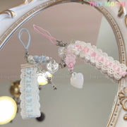 Two Kawaii Pastel Lace Ribbon Keychain – Heart & Star Bag Charms from Tiny Mochi, in blue and pink with beads and heart details, rest on a decorative mirror. The Tiny Mochi logo appears in the top right corner.