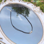 The Sterling Silver Starfish Necklace by Tiny Mochi features a handmade 925 silver charm and black beaded pearl choker, shown on an ornate mirror with reflections of greenery and sky. TINY MOCHI appears in the top right corner.