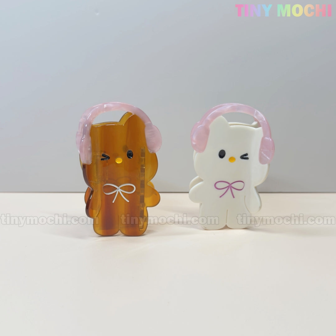 Two adorable hair claw clips—one shaped like a white bunny and the other a brown bear, both with pink headphones—make cute kawaii accessories from Tiny Mochi, perfect for adding charm to your look or bag.