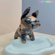 A mini French Bulldog keychain coin purse by Tiny Mochi, made of faux leather with a cute studded collar, stands on a glossy cloud-shaped surface—an adorable zipper pouch and bag charm gift for dog lovers. Pastel background features Tiny Mochi branding.