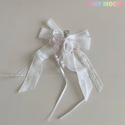 The Lace Bow Ribbon Keychain – Pearl Angelcore Bag Charm Clip by Tiny Mochi features delicate white lace, pearls, pink beads, cascading ribbons, and a metal clasp. “Tiny Mochi” appears in pastel at the top right. Perfect for keychains or angelcore style.