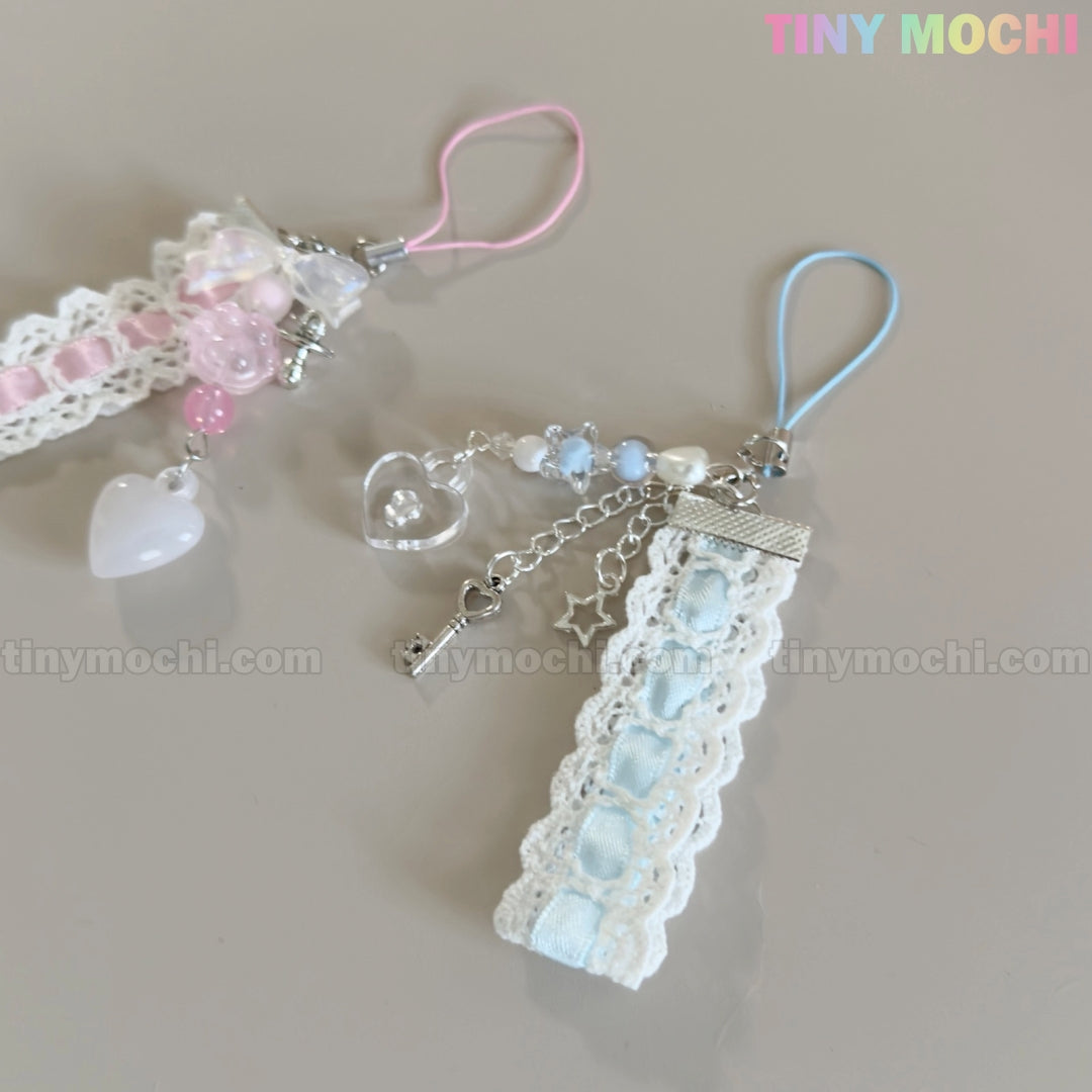 Two handmade Kawaii Pastel Lace Ribbon Keychain – Heart & Star Bag Charms by Tiny Mochi, one pink and white, one blue and white, with lace, ribbons, beads, and heart pendants are displayed on a light surface. Tiny Mochi logo at top right.