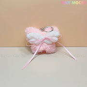 A Plush Butterfly Bow Keychain in pink with white fuzzy wings and a pink ribbon, shown on a pastel background. This Soft Girl purse accessory by Tiny Mochi adds a coquette touch. Tiny Mochi appears in the top right corner.