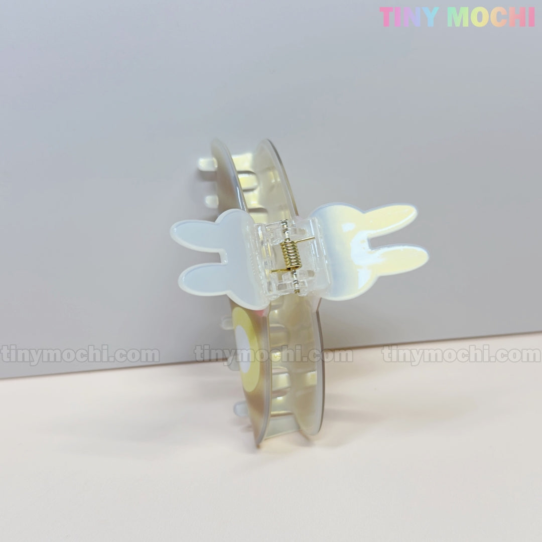 A kawaii hair claw clip shaped like a bunny with pancake and egg details rests open on a light surface. “Tiny Mochi” appears in pastel colors in the top right corner.