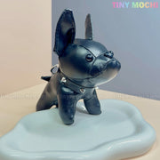 A cute black French Bulldog Keychain Coin Purse from Tiny Mochi, made of faux leather with a spiked collar, stands on a wavy white platform. “Tiny Mochi” in pastel colors appears at the top right—perfect gift for dog lovers!.