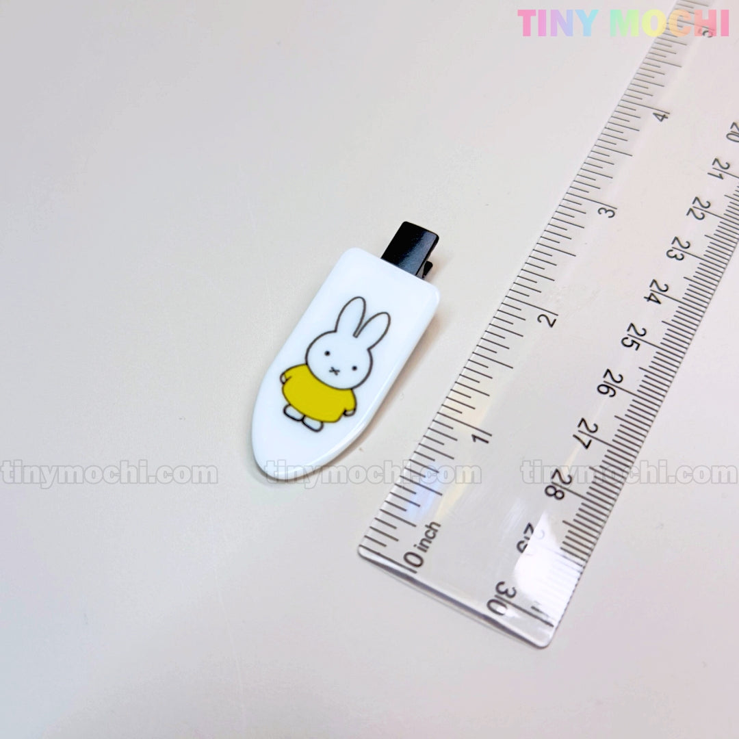 A Kawaii Bunny Hair Clip from Tiny Mochi—featuring a cute bunny in a yellow shirt—is displayed by a ruler on a white surface. This colorful cartoon resin alligator clip makes an adorable barrette gift for girls.