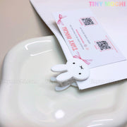 The Kawaii Bunny Paper Clip by Tiny Mochi is a cute Miffy-inspired binder clip, perfect for desk decor and organization. This adorable stationery accessory keeps papers secure and adds a charming touch to your workspace.