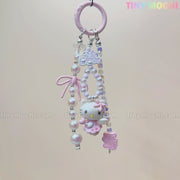 The Kawaii Pink Pearl Keychain by Tiny Mochi features a sweet kitty angel charm, pink pearl-like beads, a purple hedgehog accent, and a pink bow on a pink ring—perfect as a coquette phone or bag accessory. TINY MOCHI text appears in rainbow colors.