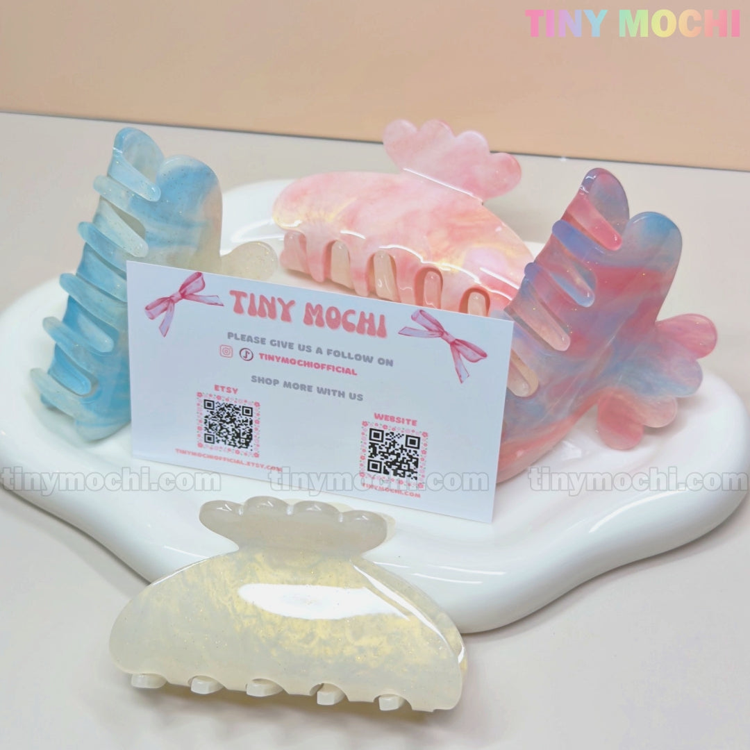 Tiny Mochi’s Pastel Hair Claw Clip—Color Changing UV Reactive Acetate Accessory for Women & Girls—adds a dreamy fairycore vibe. Displayed on a white tray, the clips sit beside a Tiny Mochi card with QR codes.
