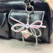The Cotton Candy Wings Charm Keychain by Tiny Mochi is a black bag accessory in kawaii fairycore style, featuring pastel beaded bows and a cute bunny charm, attached to a silver keyring—perfect as a phone or gift accessory.