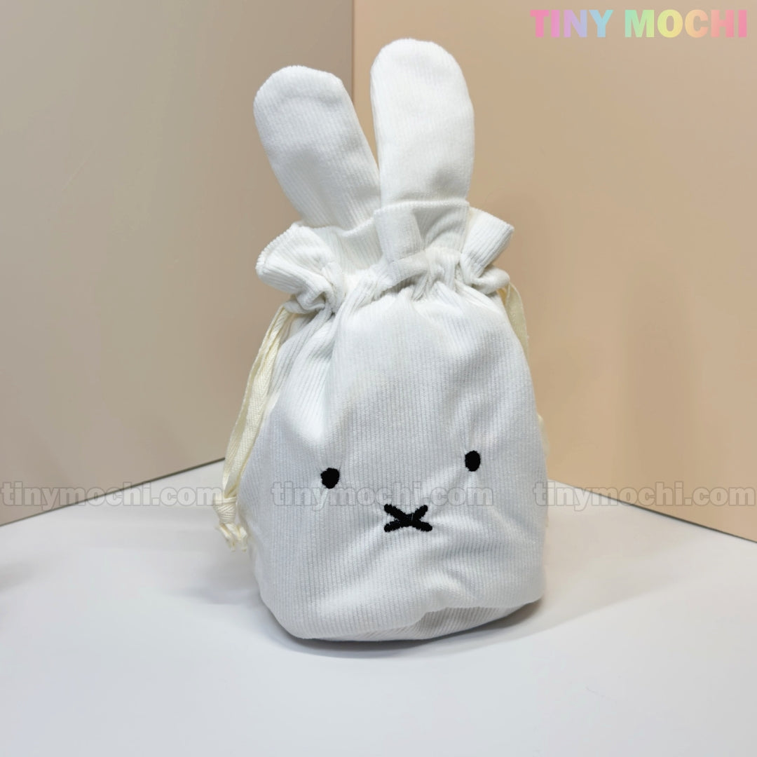 A white corduroy Kawaii Bunny & Bear Drawstring Pouch by My Store, featuring long ears and an embroidered face, sits on a light surface. TINY MOCHI in pastel colors is displayed on this cute coin makeup bag.