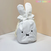A white corduroy Kawaii Bunny & Bear Drawstring Pouch by My Store, featuring long ears and an embroidered face, sits on a light surface. TINY MOCHI in pastel colors is displayed on this cute coin makeup bag.