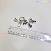 The Balloon Dog Keychain Silver Chrome Bag Charm with Star Accent by Tiny Mochi shines beside a clear ruler on a white surface, with the pastel Tiny Mochi logo in the top right, making it a cute metallic purse accessory gift.