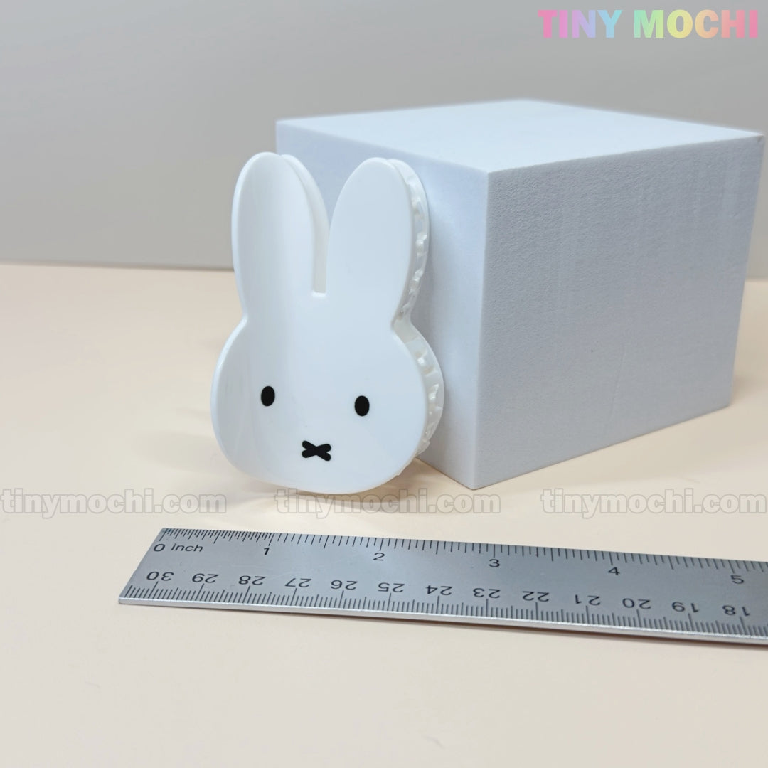 The Kawaii Bunny Face Hair Clip – White Rabbit Claw Clip by Tiny Mochi, featuring a cute bunny face design, is displayed before a white box and a centimeter ruler. Tiny Mochi appears in pastel colors at the top right.