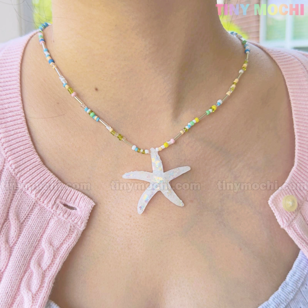 A person wears the Tiny Mochi Pastel Starfish Beach Bead Necklace—a handmade iridescent resin pendant choker with colorful beads, perfect kawaii oceancore jewelry for girls and teens.