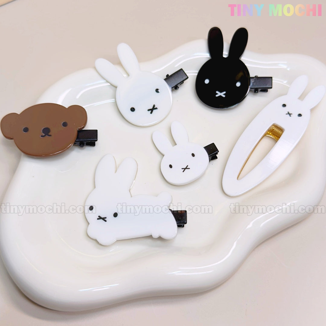 Six Tiny Mochi Kawaii Bunny and Bear Hair Clips for Girls, featuring cute cartoon animal designs with minimalist faces, are arranged on a wavy white tray. These adorable kids’ snap and alligator clips add a charming touch to any hairstyle.