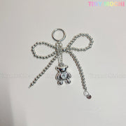 The Silver Teddy Bear Bow Keychain by Tiny Mochi, a cute bag charm for women and kawaii lovers, features silver beads and a dangling teddy bear. Displayed on a light background with tiny mochi in pastel at the top right.