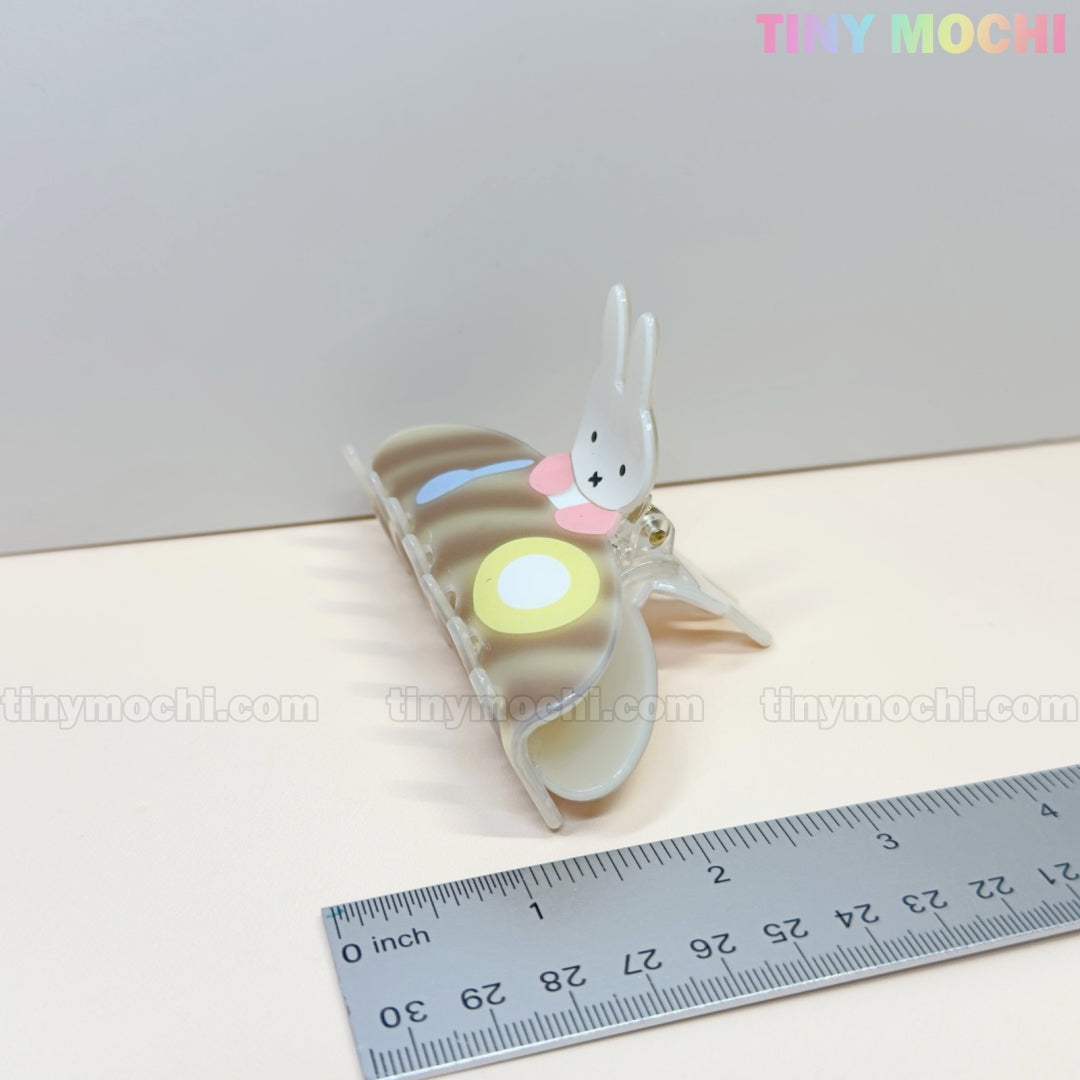 The Tiny Mochi Kawaii Bunny Breakfast Hair Claw Clip, featuring a cute pancake and egg design, sits beside a metallic ruler with cm and inch marks. The pastel background displays Tiny Mochi in the top right corner.