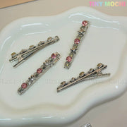 Four Kawaii Gem Hair Clips for Girls by Tiny Mochi, featuring pink gems and star accents, are shown on a white dish. Tiny Mochi appears in pastel colors at the top right against a neutral background, evoking sparkly Y2K vibes.