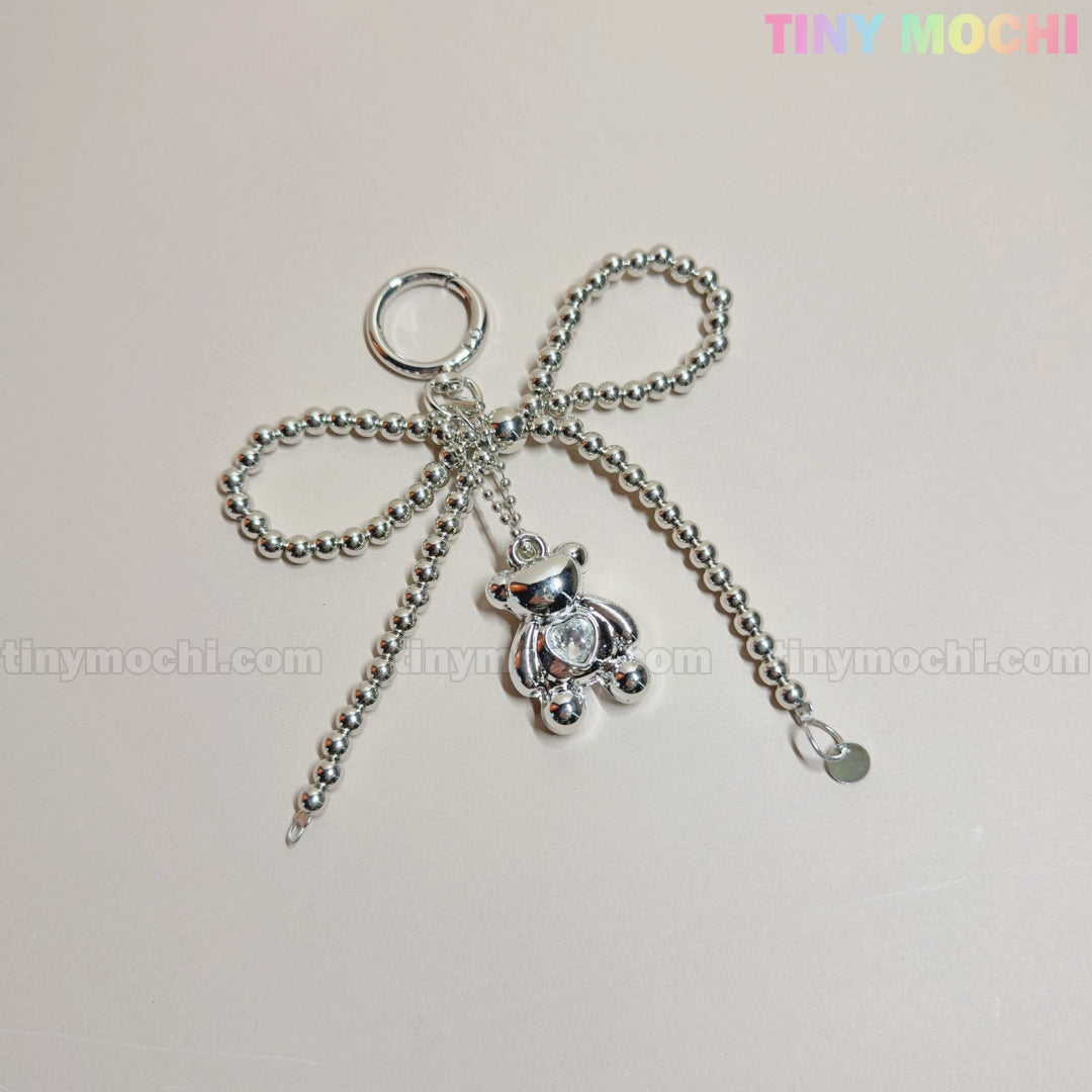 The Silver Teddy Bear Bow Keychain by Tiny Mochi is a cute bag charm accessory for women, teens, and Kawaii lovers, featuring a silver beaded bow and shiny teddy bear charm on a light background with pastel TINY MOCHI text.