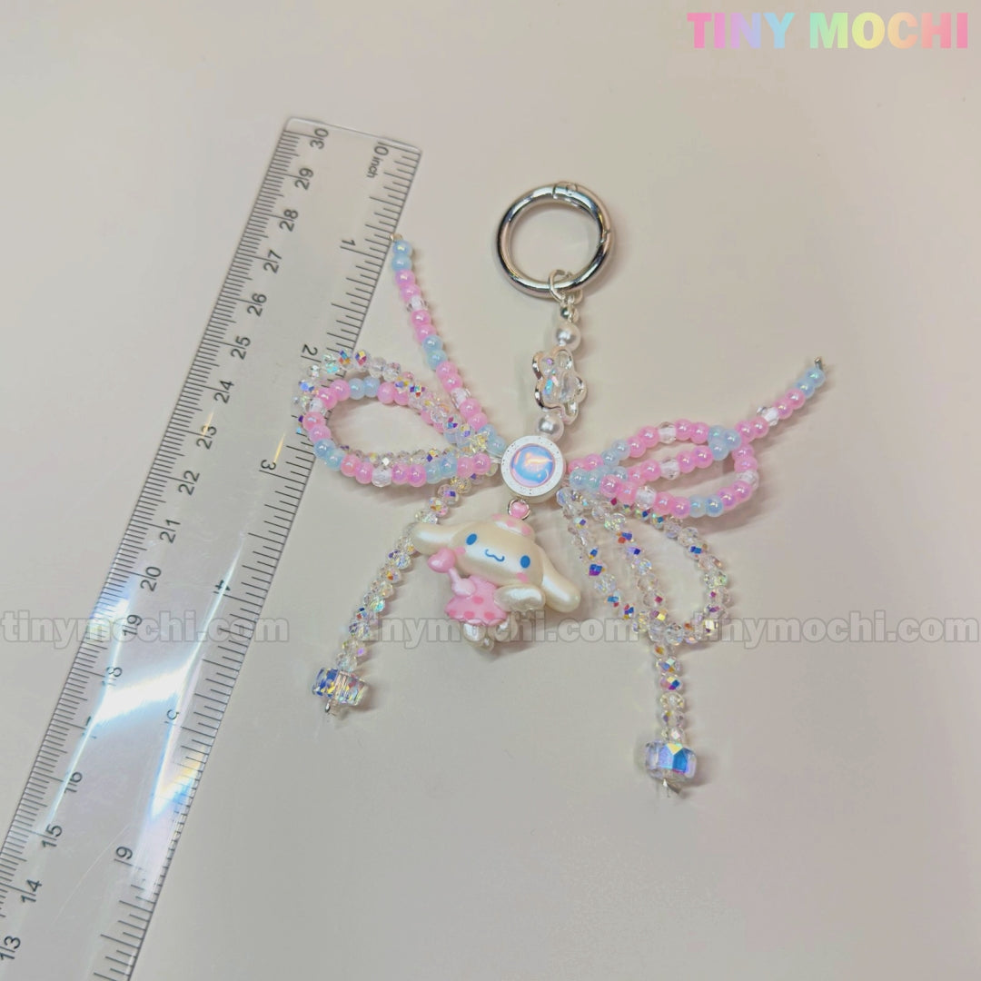 The Cotton Candy Wings Charm Keychain by Tiny Mochi, a kawaii beaded fairycore accessory with a bow, is shown beside a clear ruler on a light background. Tiny Mochi appears in pastel colors at the top right.